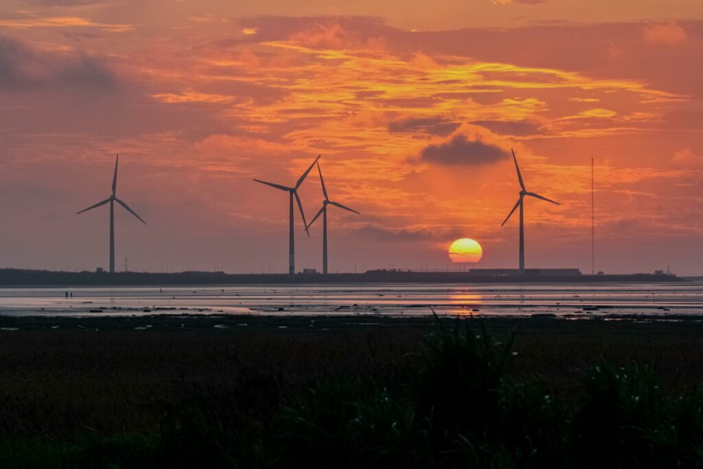 Captivating view of wind turbines silhouetted against a stunning sunset sky, promoting renewable energy.