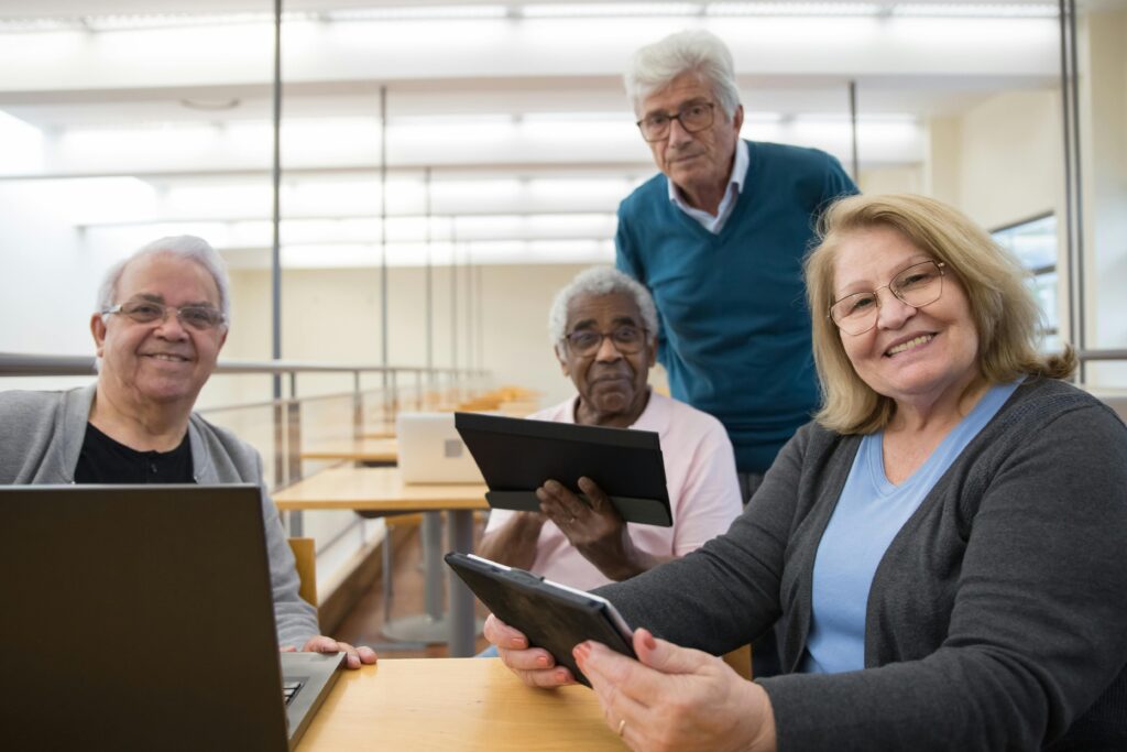 Elderly group using digital tablets and laptops in a study session indoors.